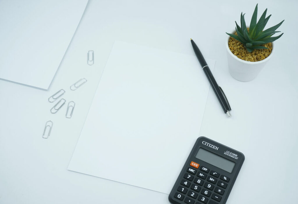 mesa con folios, boligrafo, calculadora y planta